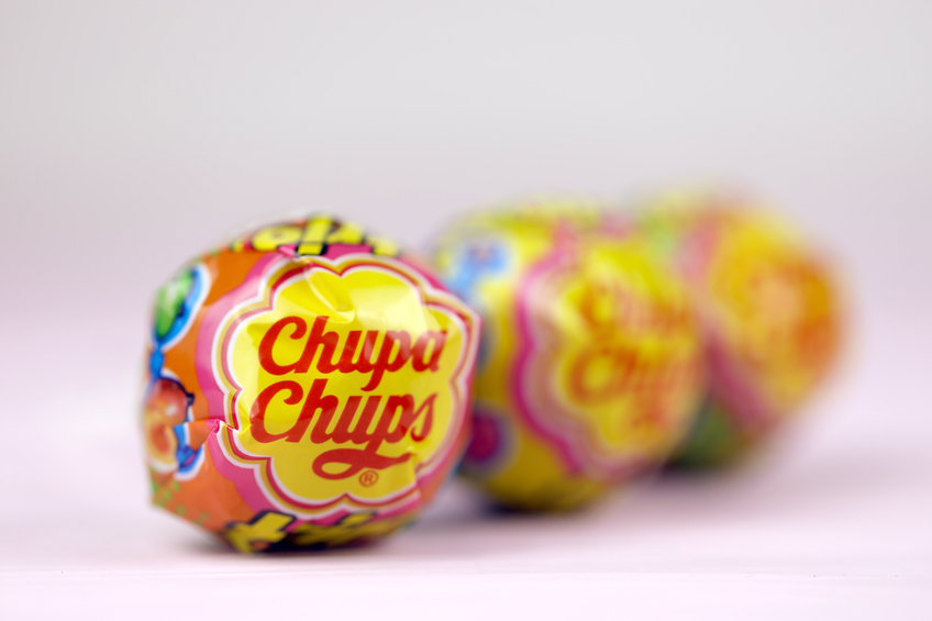 Chupa Chups products on pastel pink wooden table. Chupa Chups is a Spanish brand of lollipop and other confectionery founded in 1958 by Enric Bernat (Chupa Chups products on pastel pink wooden table. Chupa Chups is a Spanish brand of lollipop and othe
